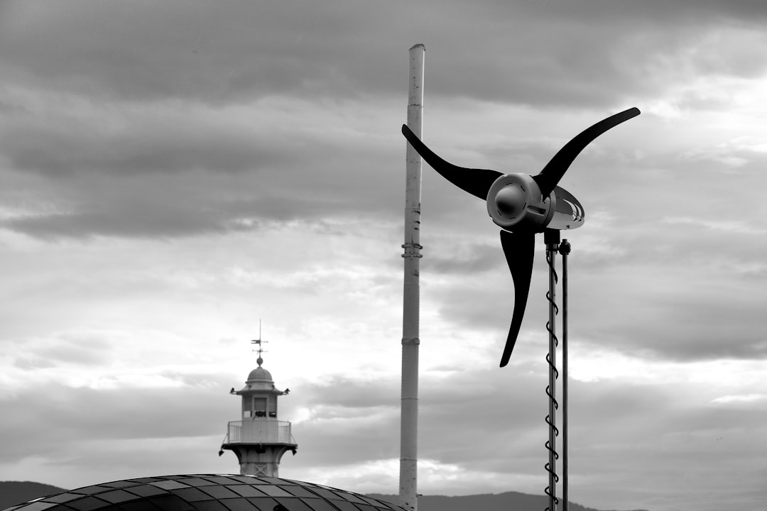 Wind turbine and lighthouse in front of cloudy sky
